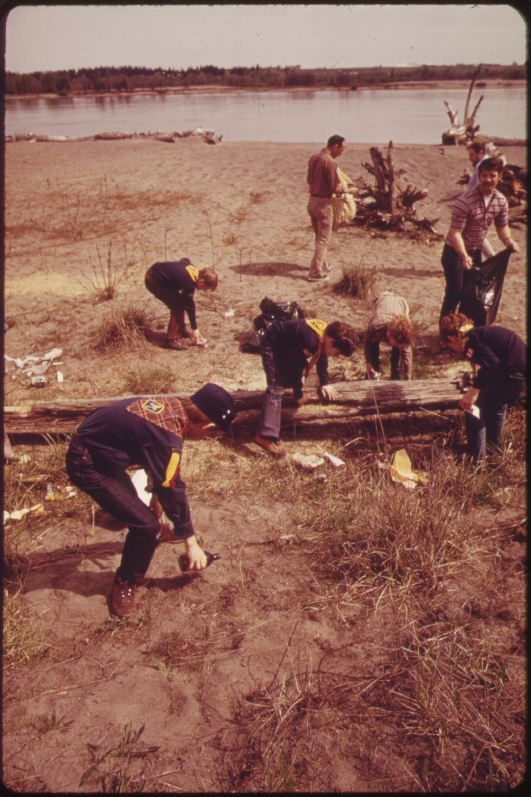 An archival photo shows a group of Boy Scouts picking up litter near a lake.