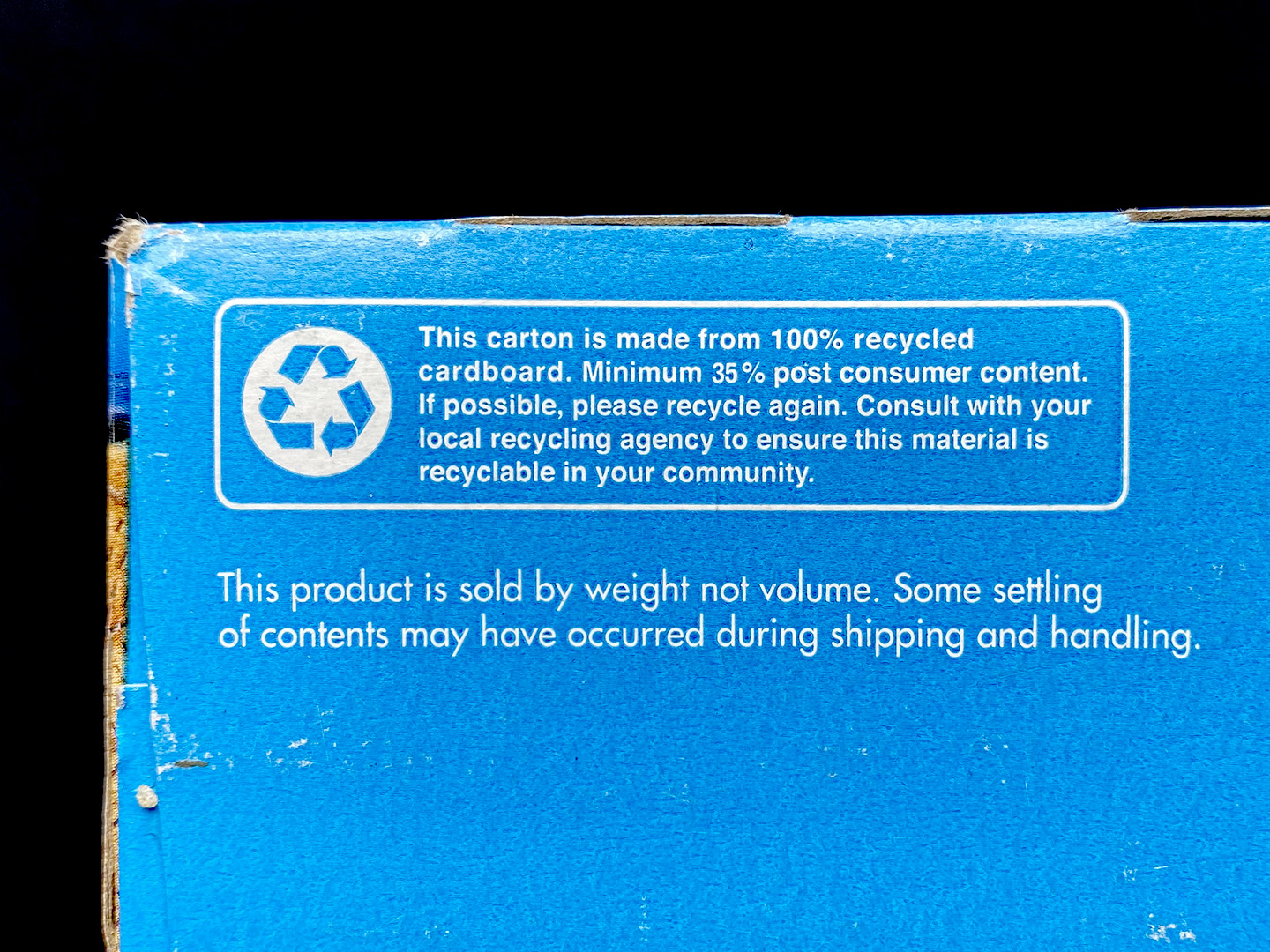 A recycling emblem on the bottom of a cereal box reads "This carton is made from 100% recycled cardboard. Minimum 35% post consumer content. If possible, please recycle again. Consult with your local recycling agency to ensure this material is recyclable in your community".